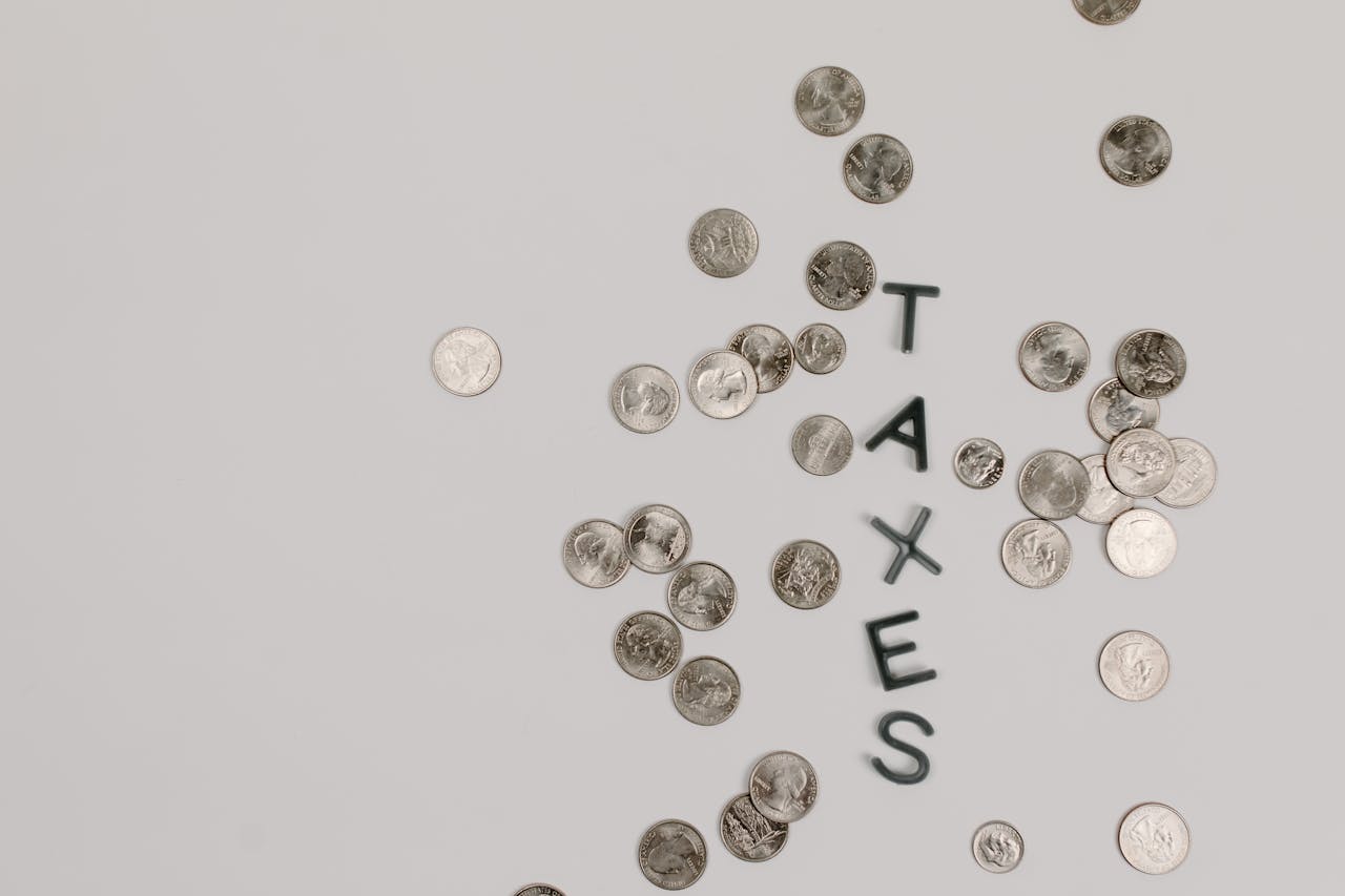 Scattered coins forming the word TAXES on a white surface, symbolizing financial concepts.