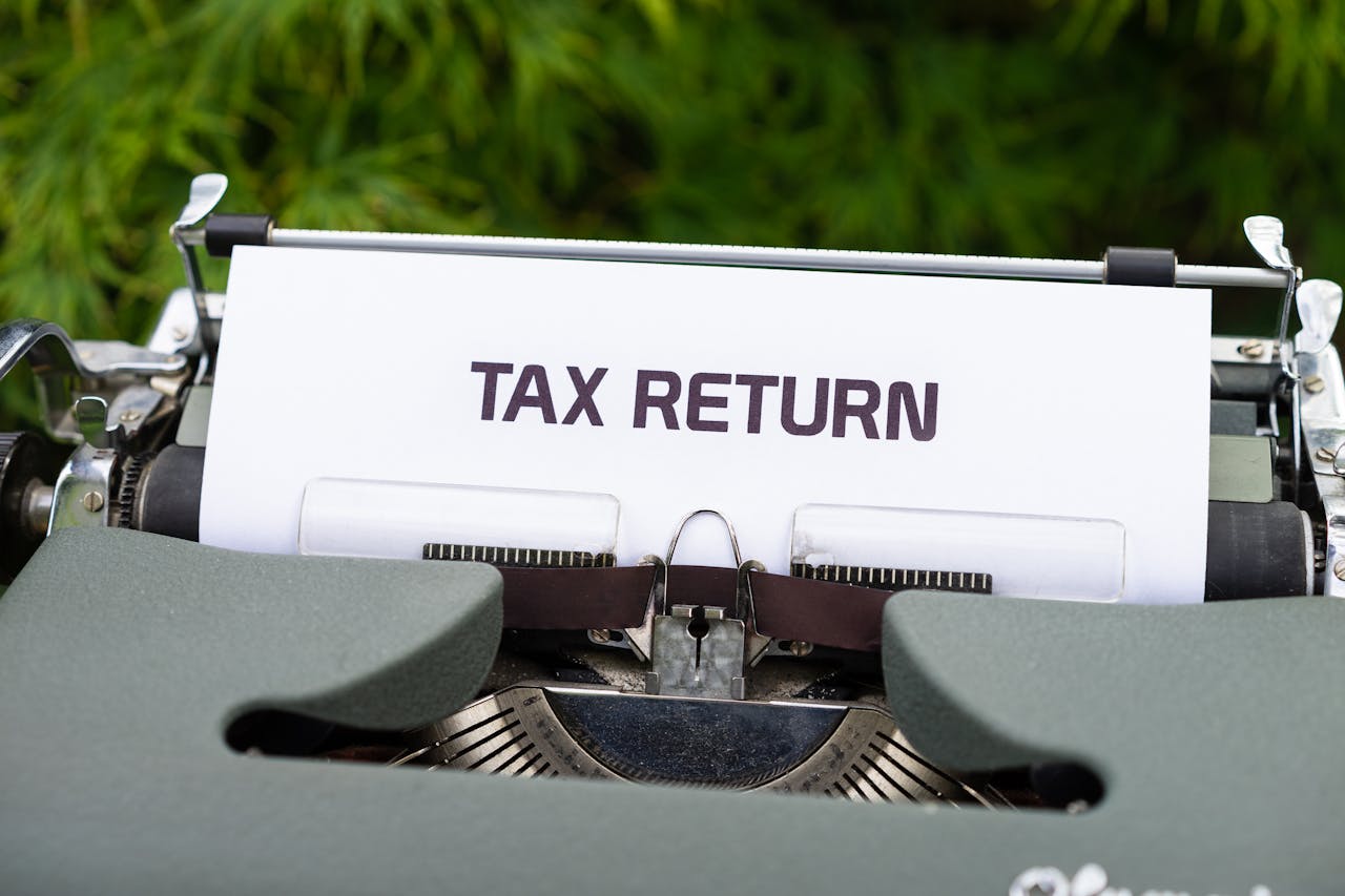 Close-up of a vintage typewriter typing Tax Return on paper outdoors.